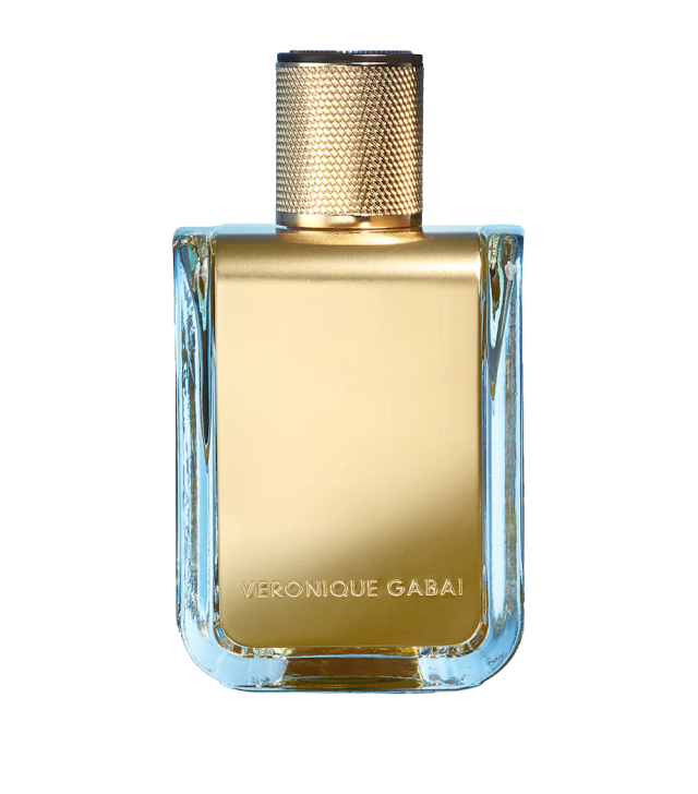 A rectangular perfume bottle displays a shiny gold label and textured gold cap, with 