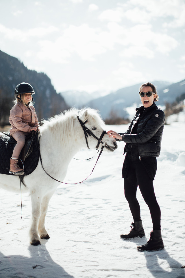 Girl riding white pony in snow.