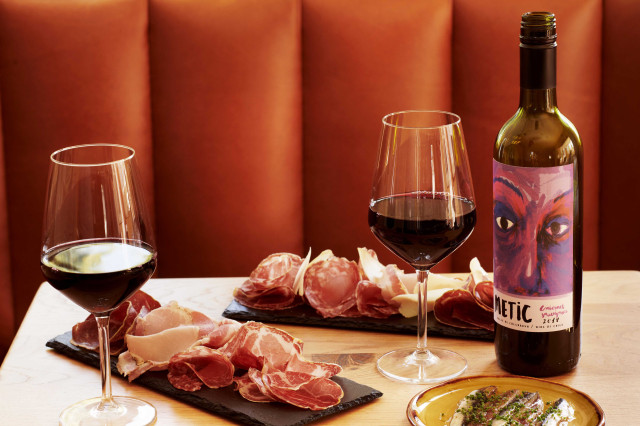 Two wine glasses filled with red wine, accompanied by a bottle labeled 