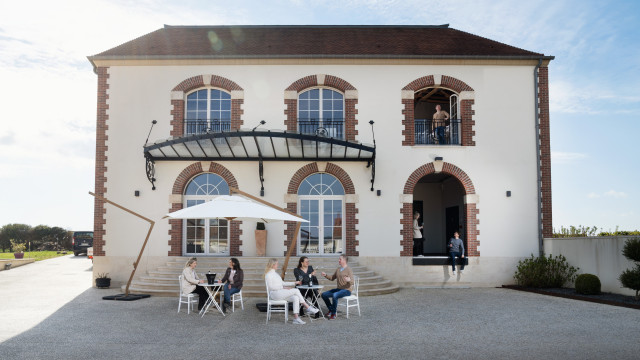 People socializing near white building.