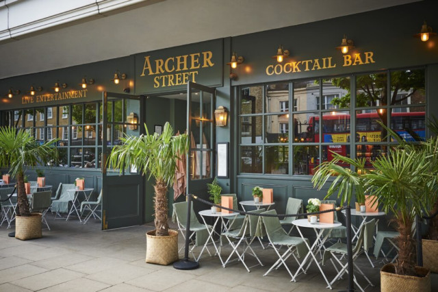 Outdoor seating features folded chairs and tables with potted plants outside 