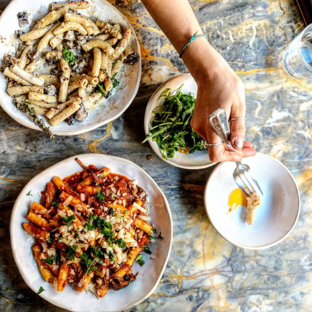 Pasta dishes and salad on a marble table.