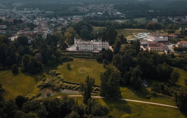 White castle in a green landscape above a town.