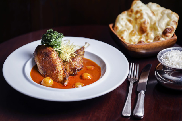 Roasted chicken with sauce and sides on a plate.