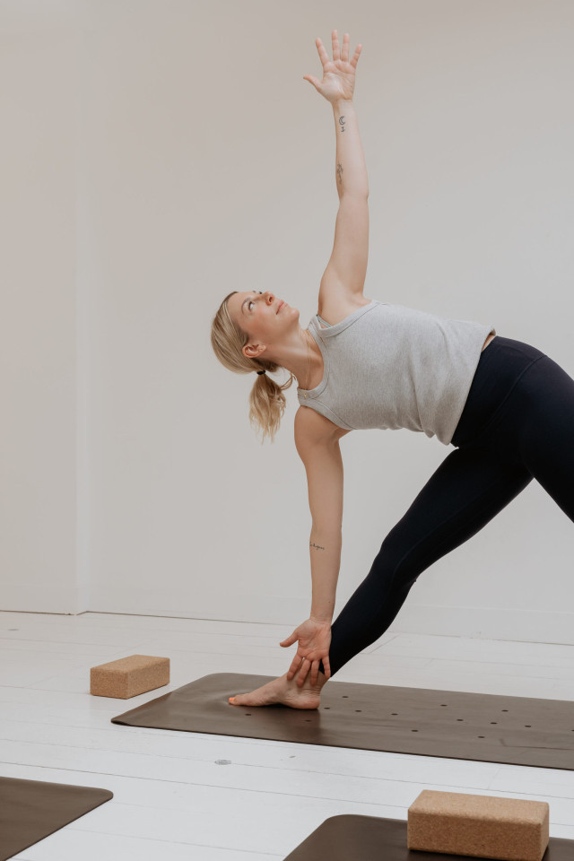 Woman in yoga pose on a mat in a bright room.