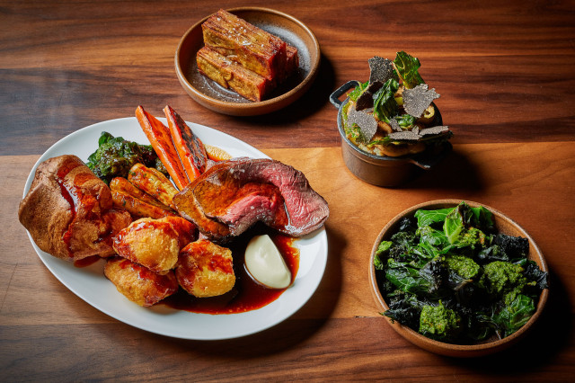 Roast beef and sides on wooden table.