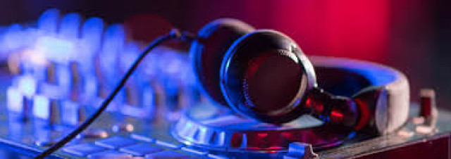 Over-ear headphones on a DJ mixer with blue and red lights.