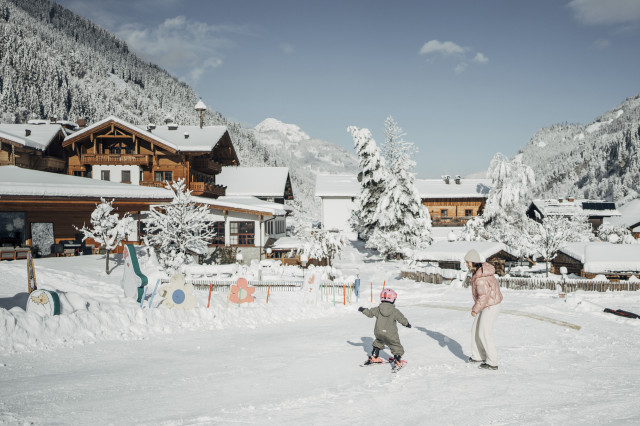 Kids skiing snowy village scene.