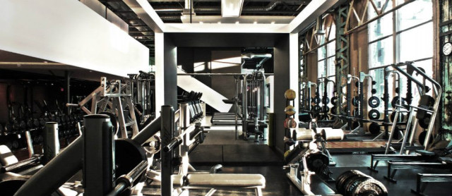 Weightlifting equipment in a spacious, industrial-style gym.