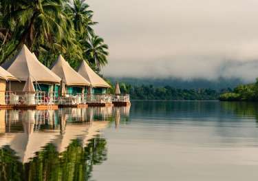 Floating tents by puffy cloud river.