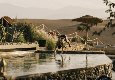 Woman diving into pool in desert setting.
