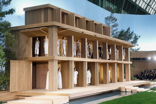 Model in flowing embroidered gown on runway.