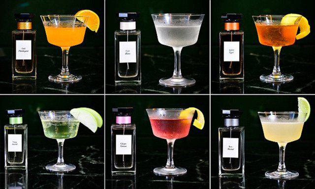 Six cocktails in elegant glasses, each with unique garnishes, sit next to matching perfume bottles against a dark background