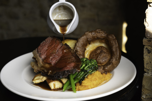 Gravy drizzled on roast beef and sides.