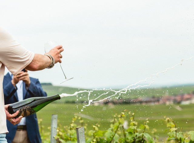 Champagne bottle popped in vineyard.