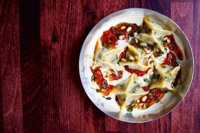 Pasta in creamy sauce with red peppers and herbs in a metallic bowl.