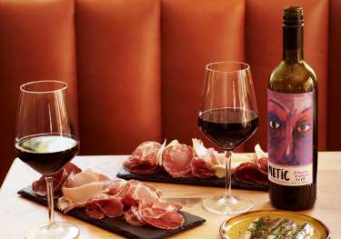 Two wine glasses filled with red wine, accompanied by a bottle labeled 