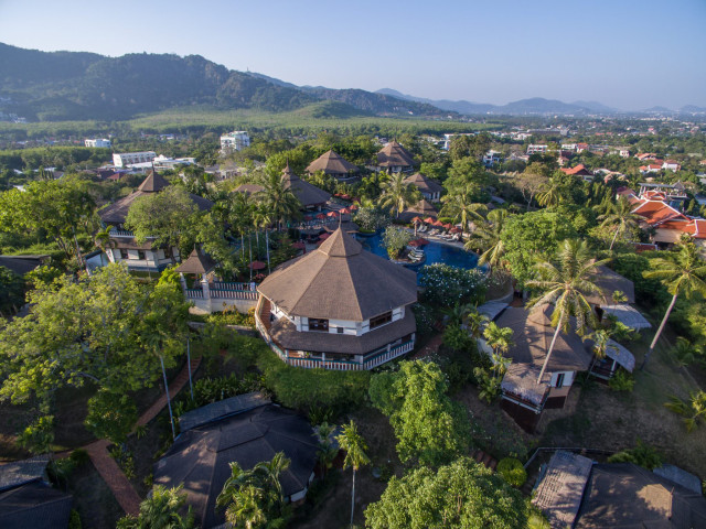 Circular buildings with thatched roofs sit among lush tropical greenery
