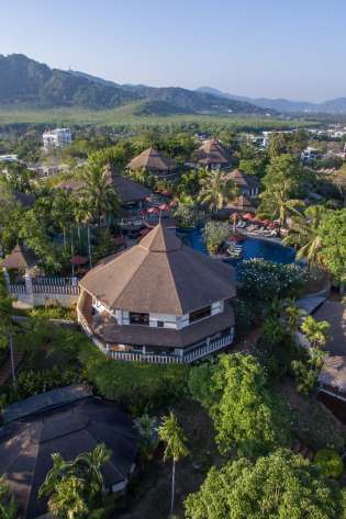Circular buildings with thatched roofs sit among lush tropical greenery.