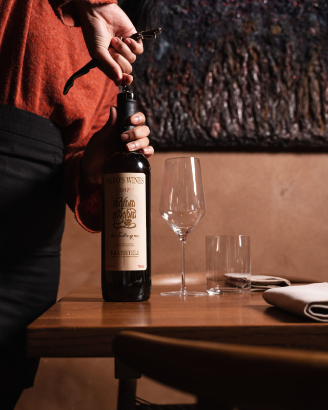 A person opens a wine bottle labeled 