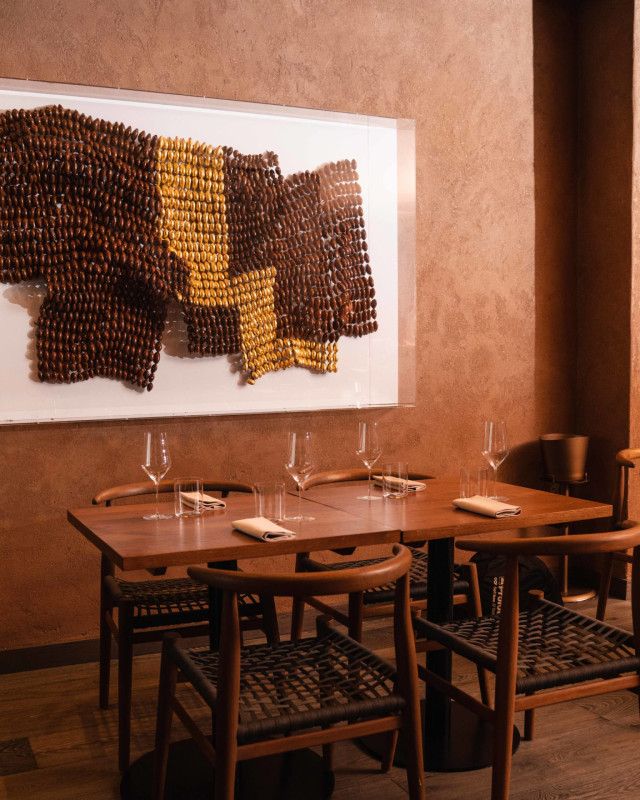A wooden table holds neatly arranged glasses and napkins, while four chairs surround it