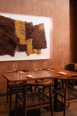 A wooden table holds neatly arranged glasses and napkins, while four chairs surround it.