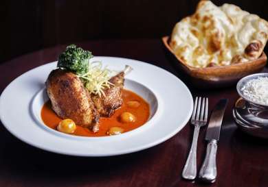Roasted chicken with sauce and sides on a plate.