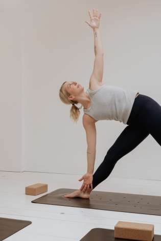 Woman in yoga pose on a mat in a bright room.