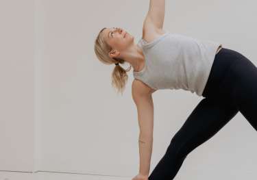 Woman in yoga pose on a mat in a bright room.