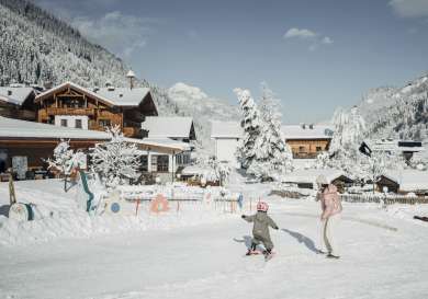 Kids skiing snowy village scene.