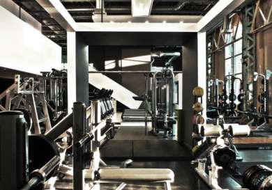 Weightlifting equipment in a spacious, industrial-style gym.