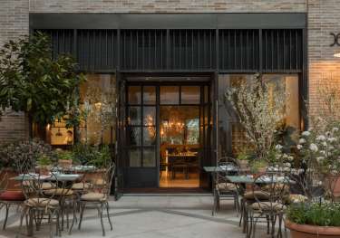 Outdoor patio with tables, chairs, and warm restaurant lighting.