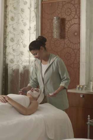 Woman applying a facial mask in a luxury spa.