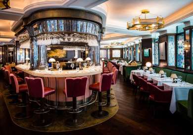 Restaurant bar with glassware, stools, and wood floors.