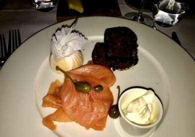 Smoked salmon served with sauce and bread on a plate.