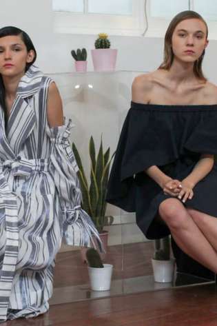 Two women are seated in a minimalist, plant-filled room.