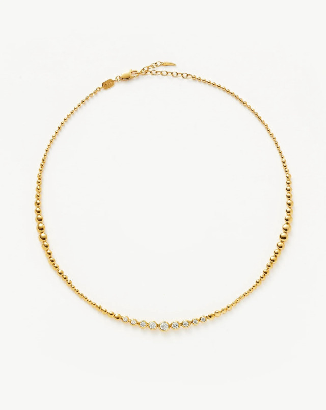Gold necklace with diamonds on white background.