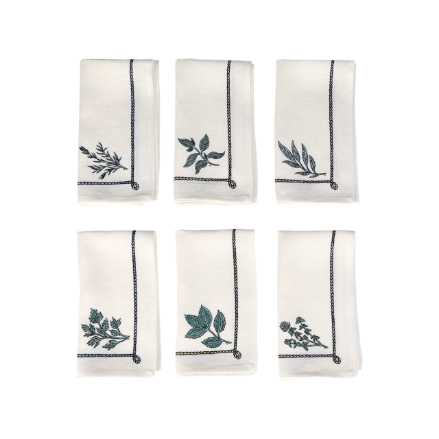 White cloth napkins feature embroidered green leaves, arranged in two rows of three, each showcasing a unique leaf design and bordered by black decorative stitching on a white background.