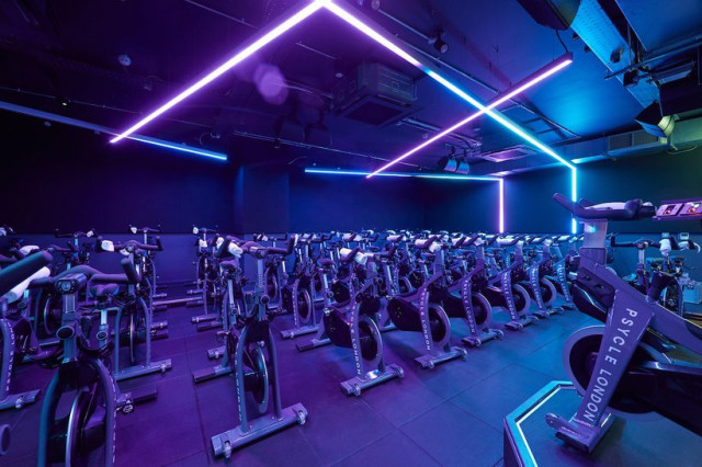 Stationary bikes in neon-lit room.