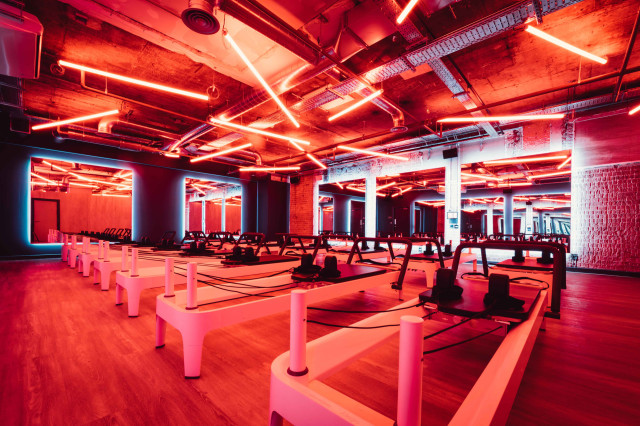 Pink Pilates reformers in dim studio.