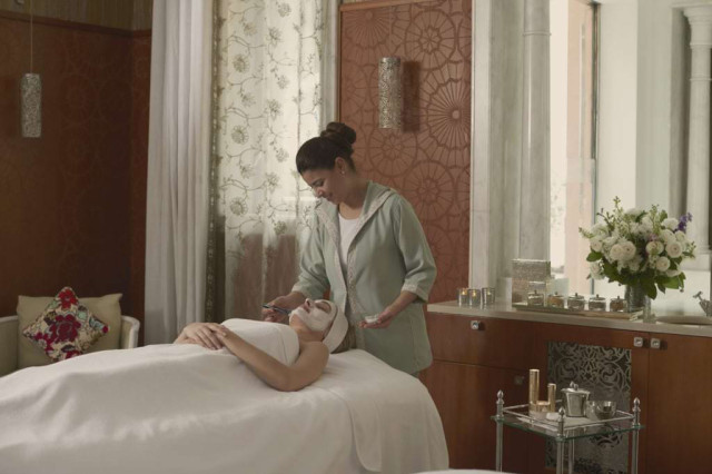 Woman applying a facial mask in a luxury spa.