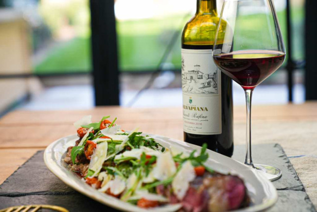 A glass of red wine and a bottle labeled 