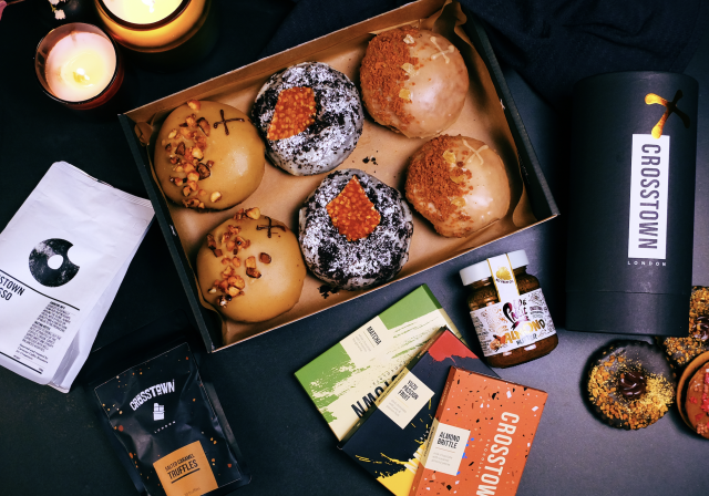 Assorted doughnuts with packaging on a dark table.