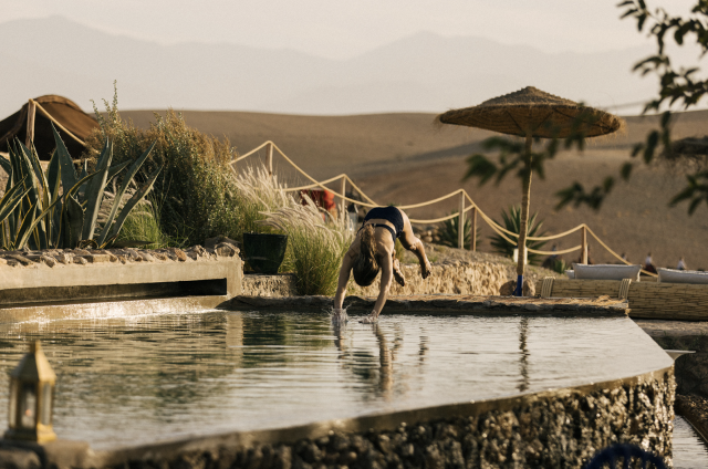 Woman diving into pool in desert setting.