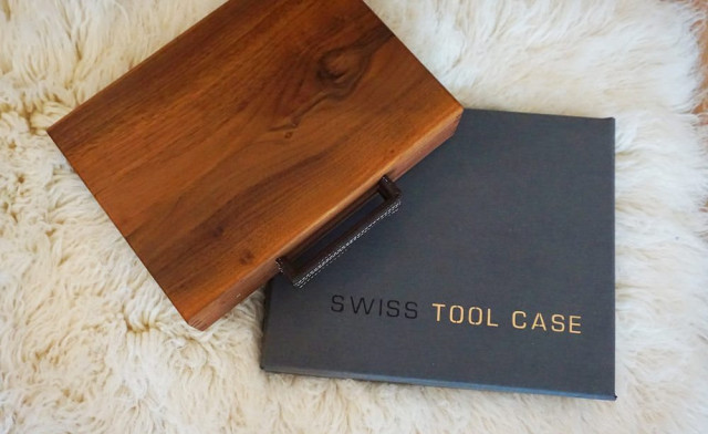 A wooden box lies open on a fluffy white rug, partially revealing a closed case labeled 