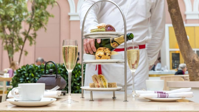 Tiered stand with pastries and champagne at an outdoor café.