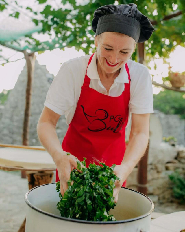 Chef adding greens to bowl.
