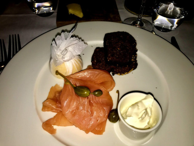 Smoked salmon served with sauce and bread on a plate.