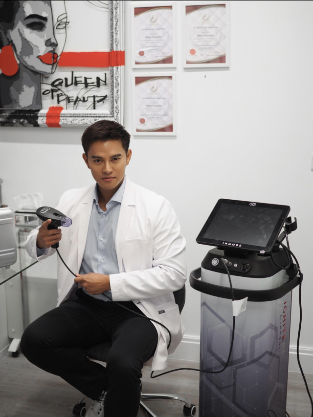 A person in a white coat holds a handheld device connected to a machine labeled 
