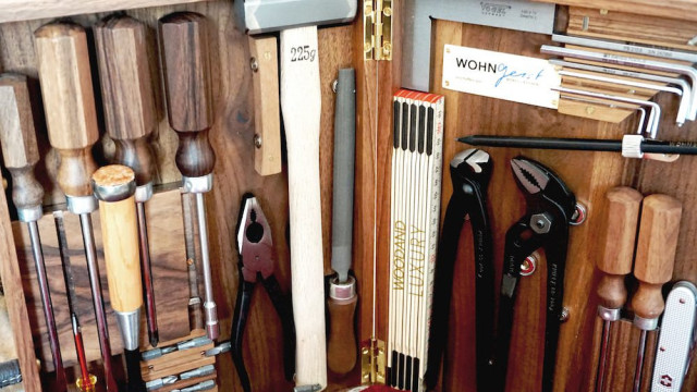 A wooden toolbox contains assorted tools: hammers, chisels, pliers, and clamps, organized neatly